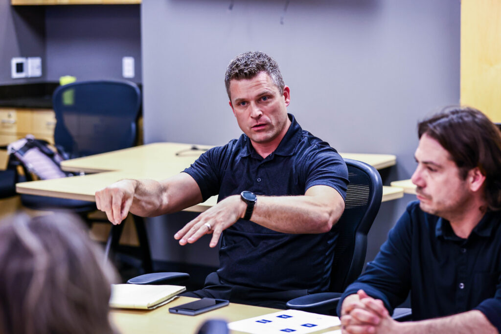 Two Iowa Western staff members discuss materials during a meeting in a campus conference room.