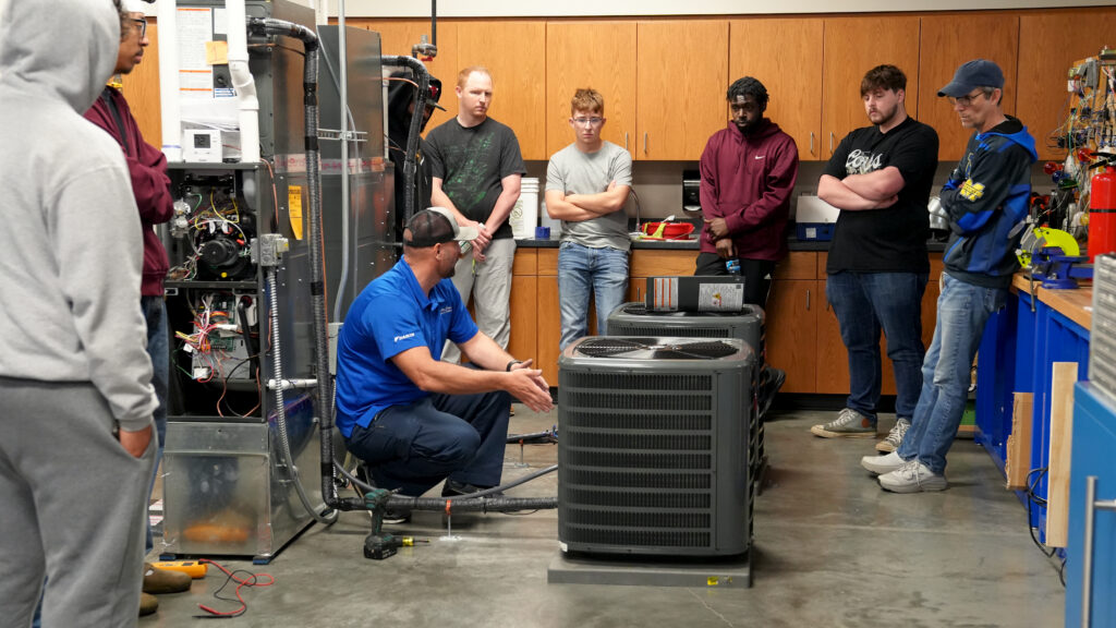 Iowa Western students gather around an instructor going over HVAC information